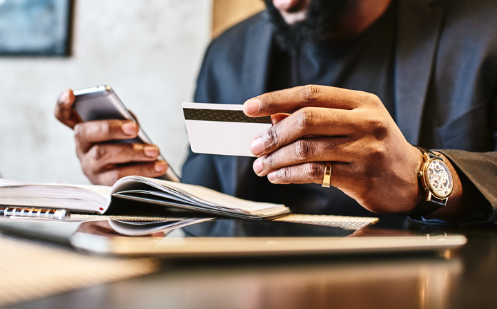 Male using his cellphone while looking at his credit card
